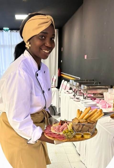 A Chef Macuta com uma tábua de frios junto a uma mesa de buffet